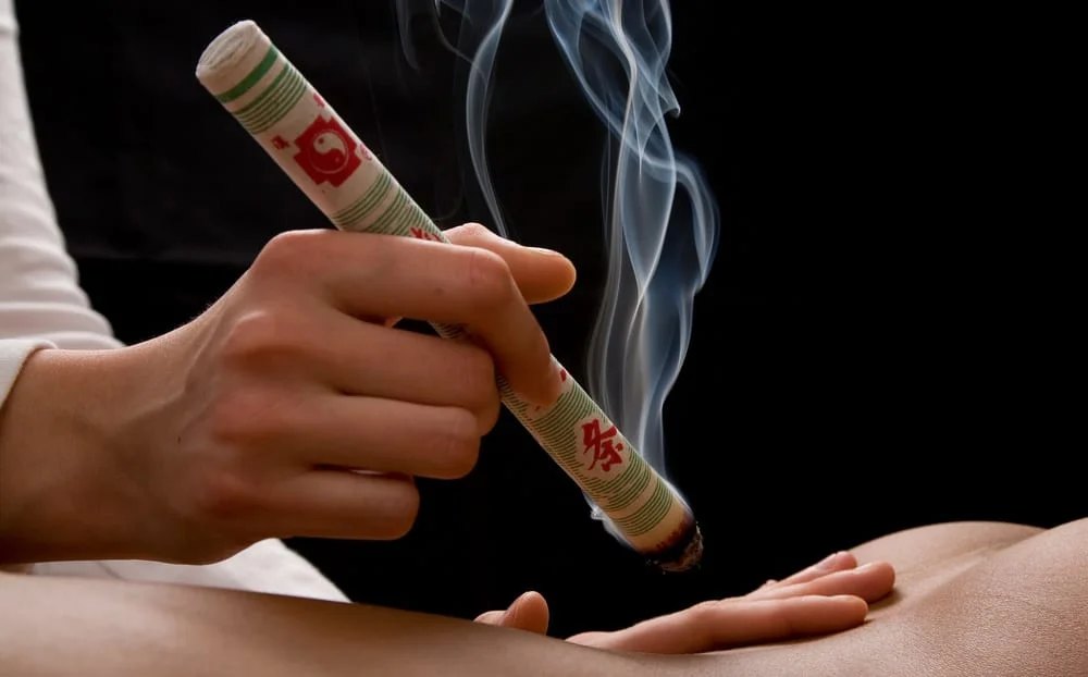 Moxibustion avec un bâton d'armoise tenu au-dessus du corps